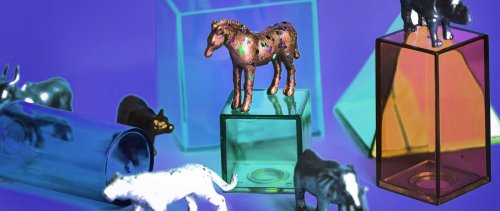 A toy horse on a glass plinth surrounded by a other toy animals